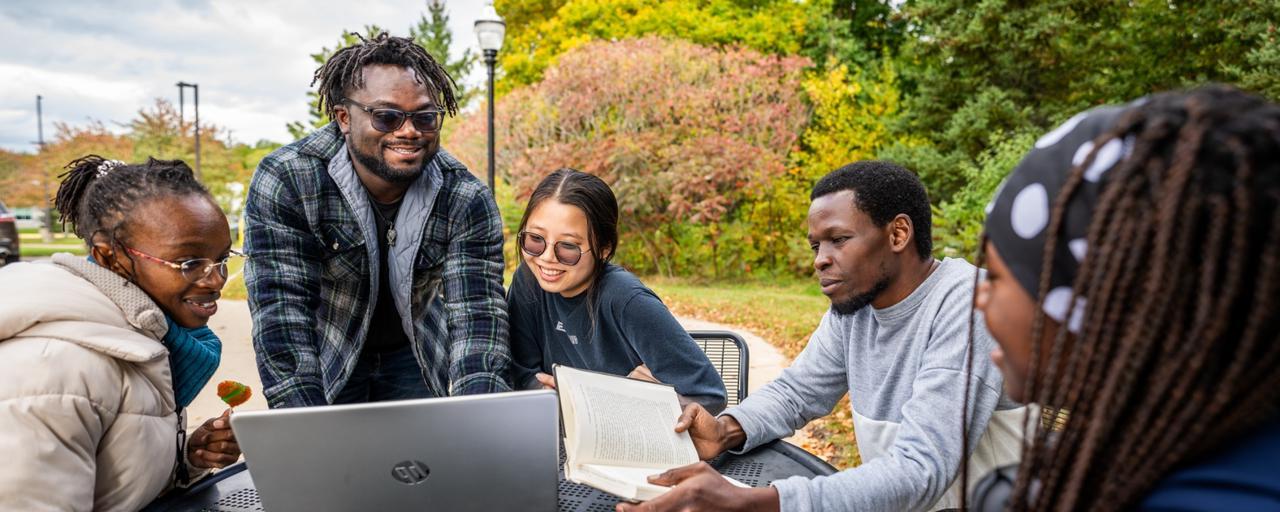 International students gather around a table outside laughing